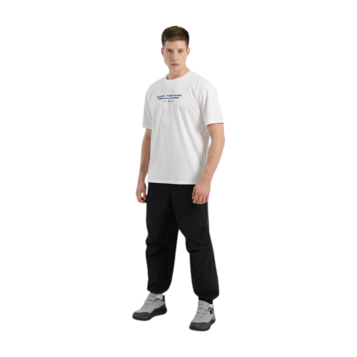 A man wearing FRG COMMUTE relaxed black woven textile trousers with a white t-shirt and grey sneakers.