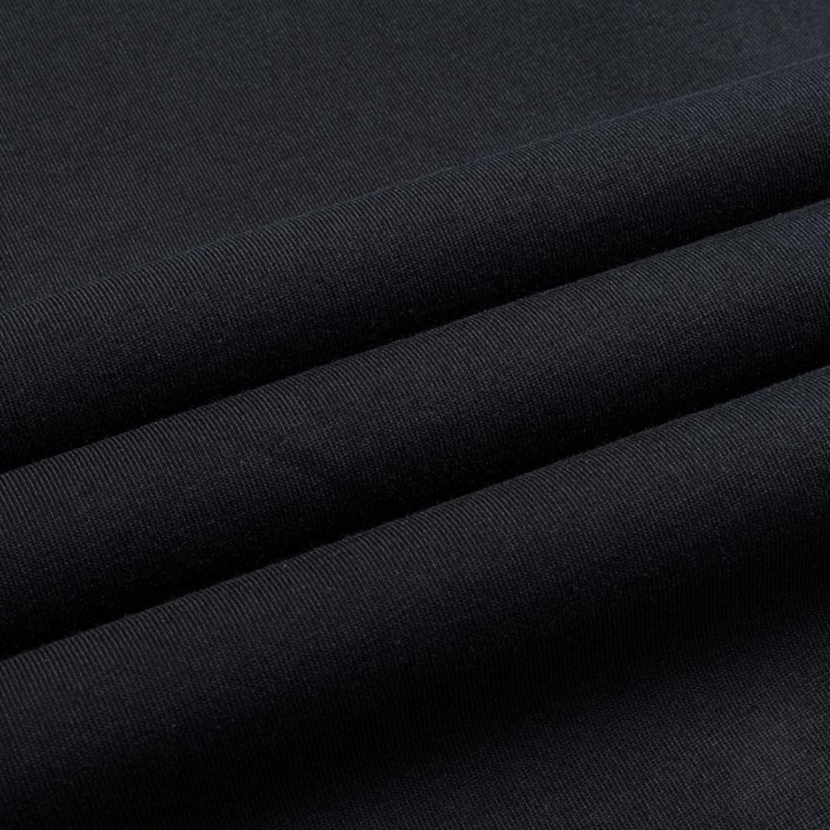 Close-up of the black cotton fabric texture of a FRG SS TEE showing the fine knit detail.