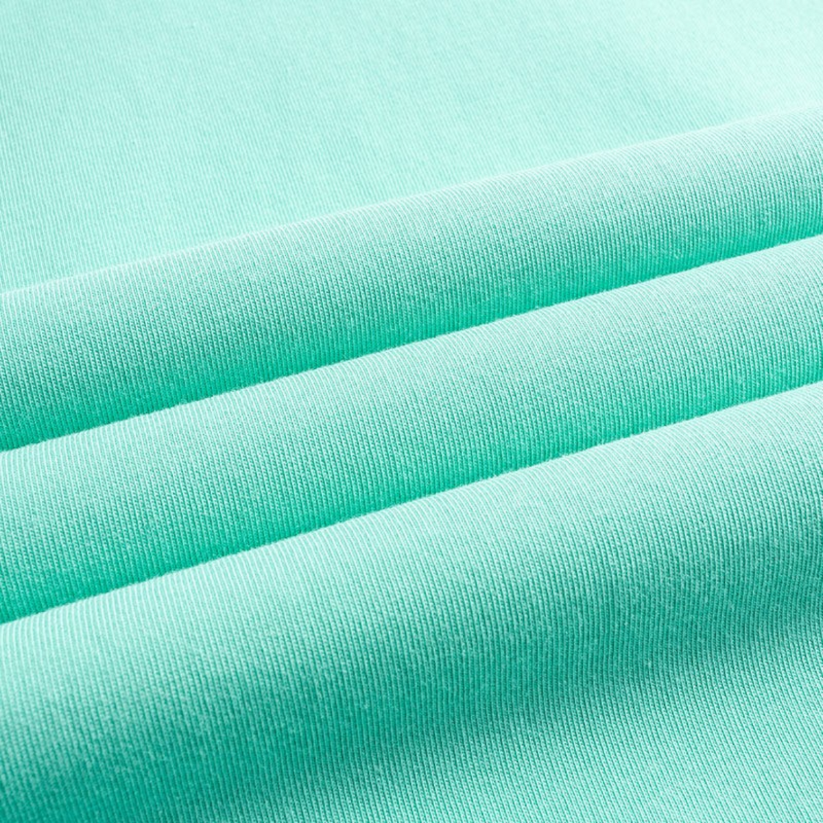 Close-up of soft mint green cotton fabric from a FRG SS TEE showing the smooth texture and draped folds.