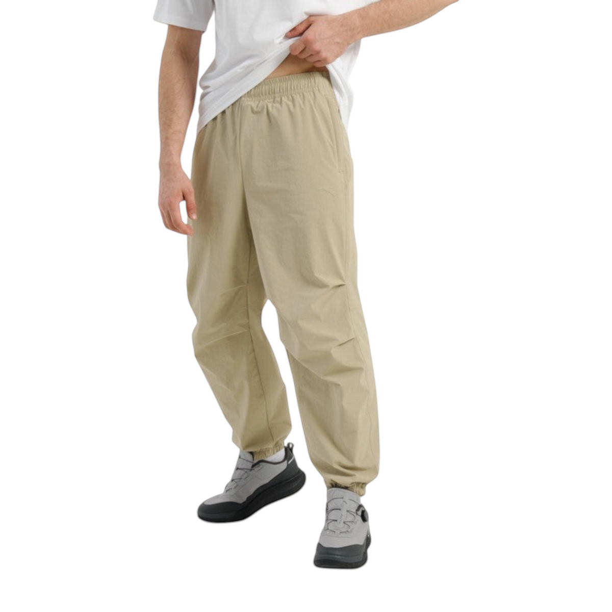 FRG COMMUTE relaxed beige woven track pants with an elastic waistband and cuffed ankles worn by a man