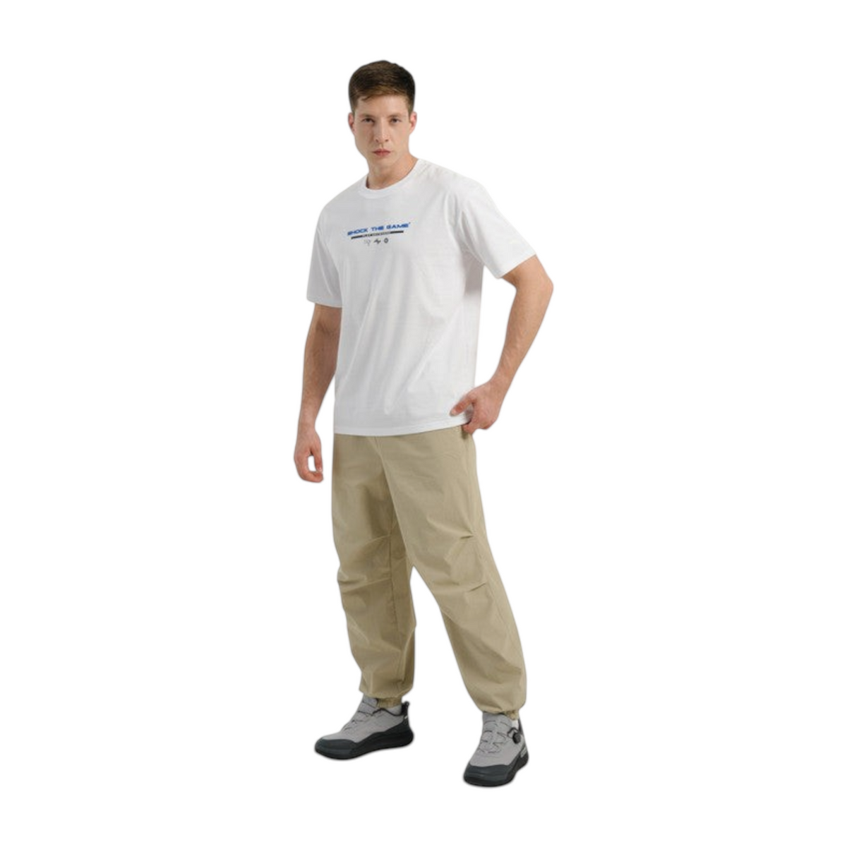 FRG COMMUTE relaxed woven track pants in beige worn by a male model with a white graphic t-shirt and grey sneakers