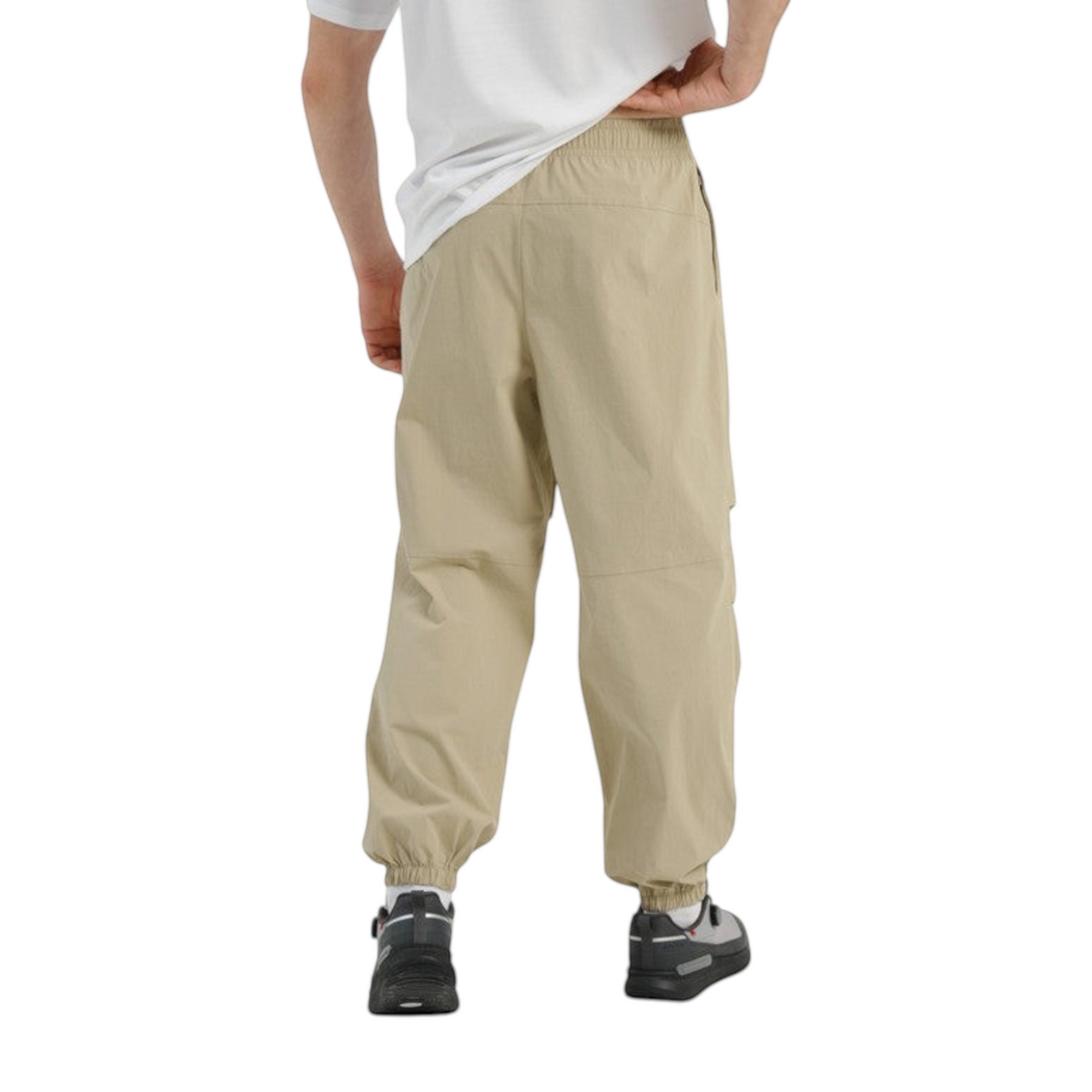 Back view of FRG COMMUTE relaxed beige woven track pants with elasticated cuffs worn by a model.