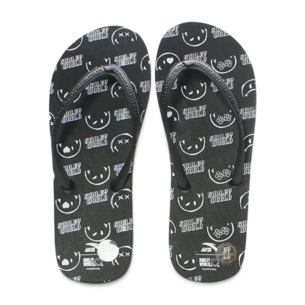 FRG beach slippers in black featuring a white Smiley World pattern with various expressive faces and floral icons