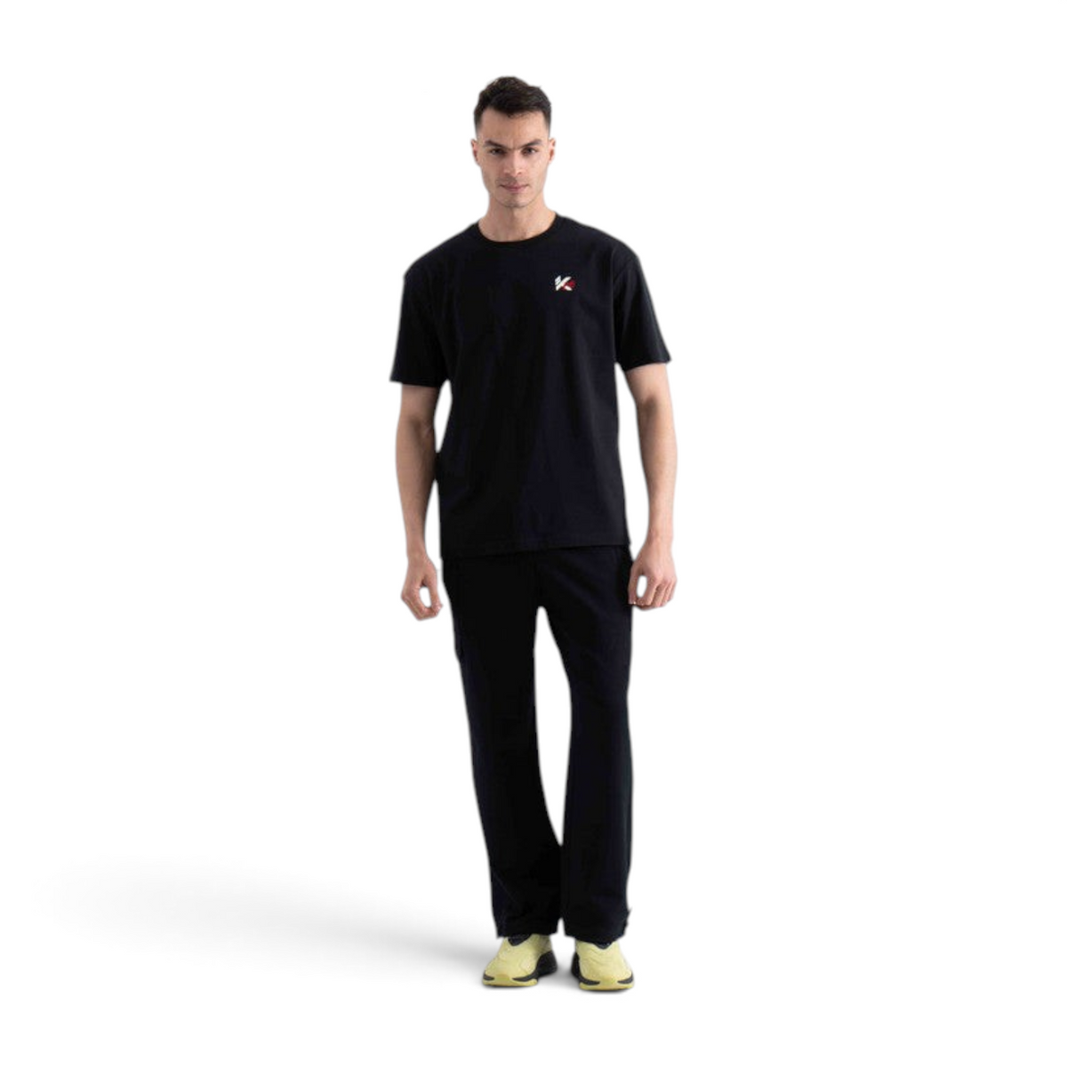Model wearing a black FRG short sleeve t-shirt with a small logo on the chest, paired with black trousers.