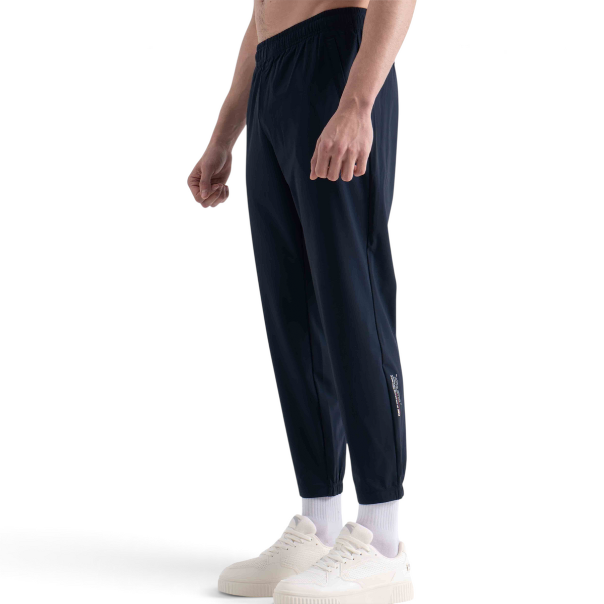 FRG navy blue knit ankle pants with a tapered fit and subtle side leg detailing worn by a man with white sneakers.
