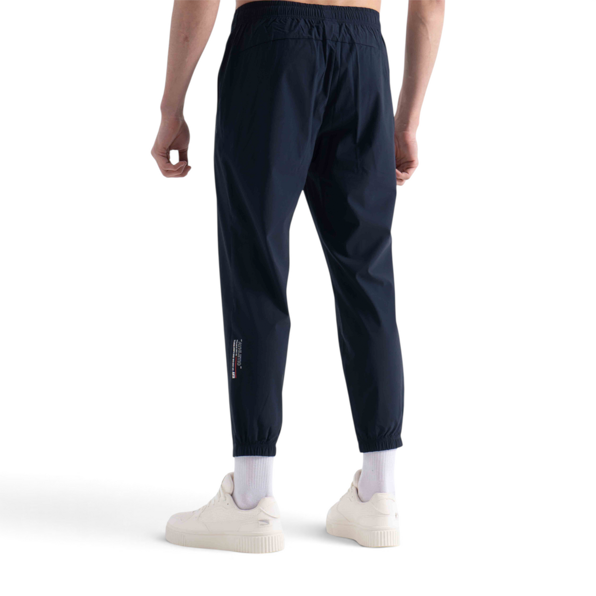 FRG knit ankle pants in navy blue with elastic cuffs and a small graphic detail on the lower leg, back view
