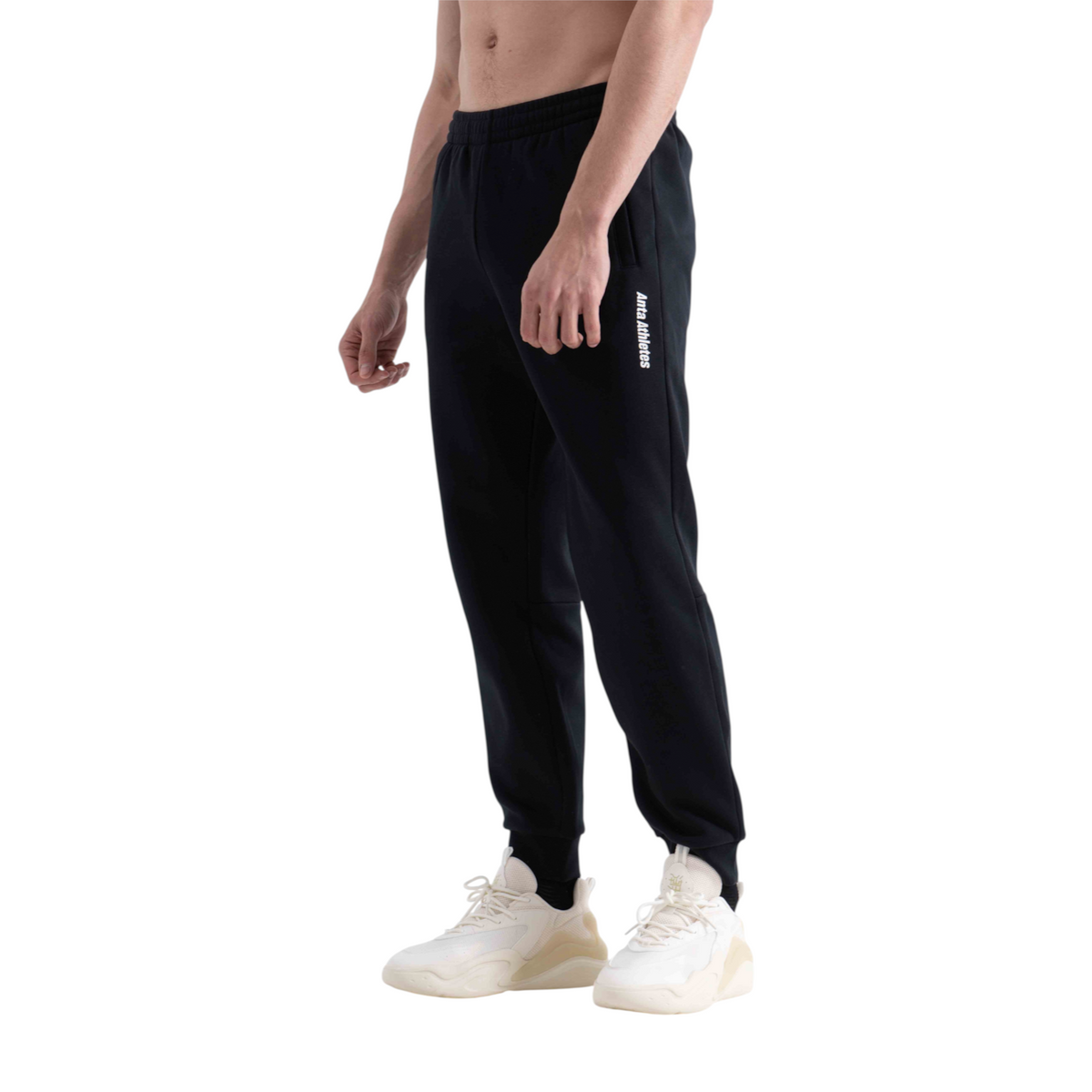 FRG black knit track pants with elasticated cuffs and white logo detail worn by a man with white sneakers