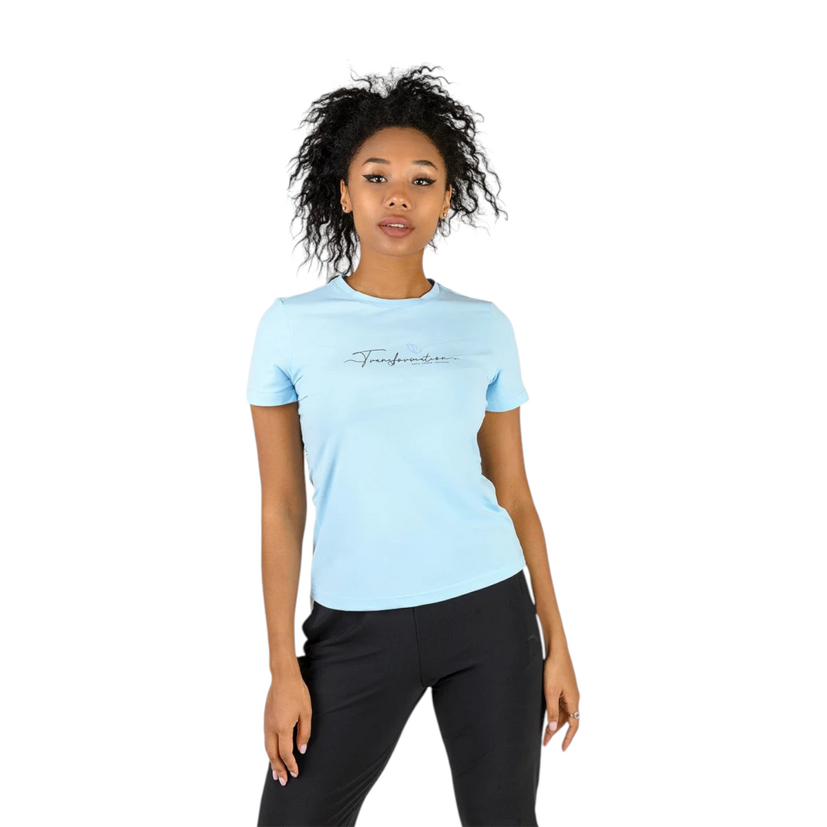 A woman wearing a light blue FRG cross training t-shirt with Transformation script logo on a plain background