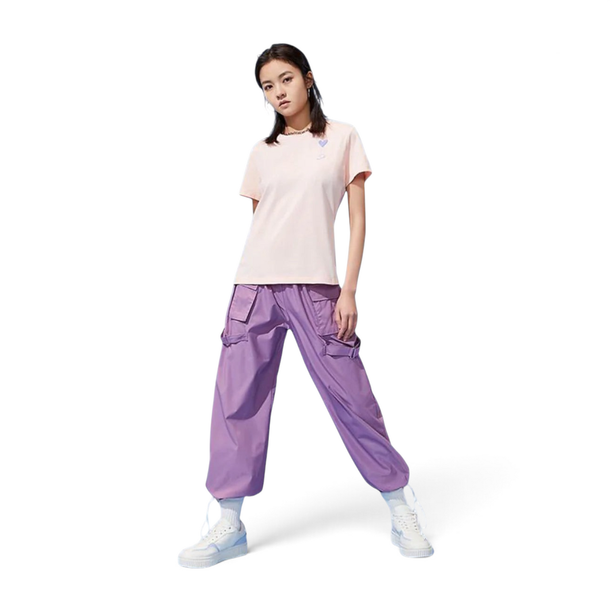 FRG light pink t-shirt with a small heart detail worn with purple cargo pants by a model on a white background
