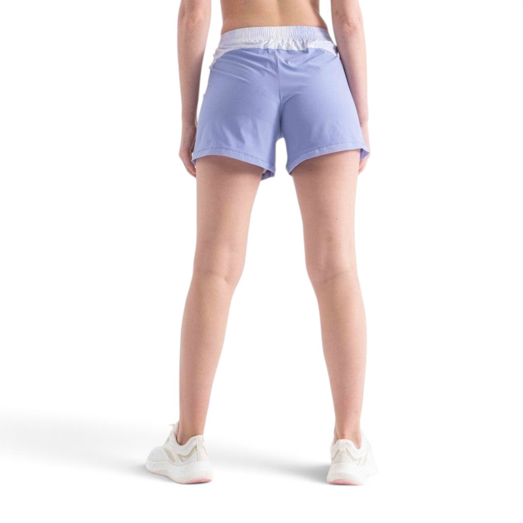 Back view of a woman wearing FRG light purple athletic shorts with a white waistband on a white background