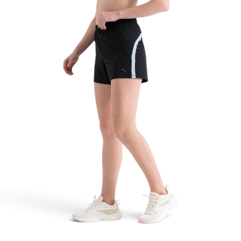 FRG black athletic shorts with side reflective stripe worn by a woman with white sneakers