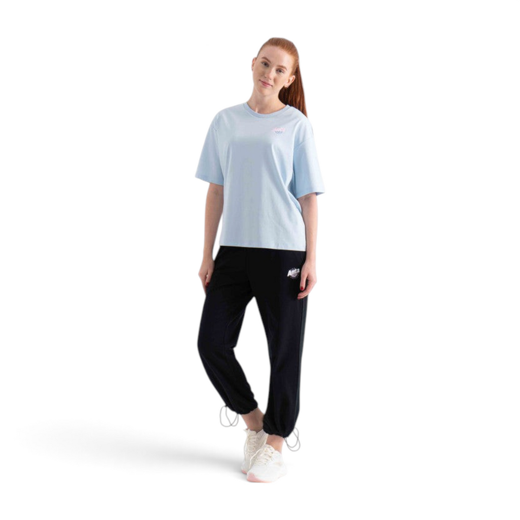 A model wearing a light blue FRG SS TEE with a small logo, paired with black joggers and white sneakers.
