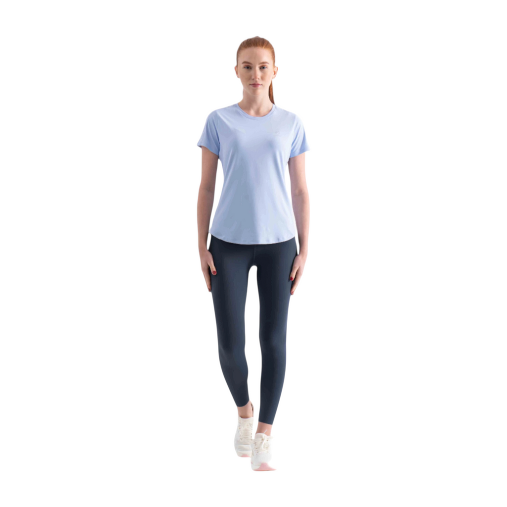 FRG SS TEE in light blue worn by a woman with dark leggings and white sneakers against a white background