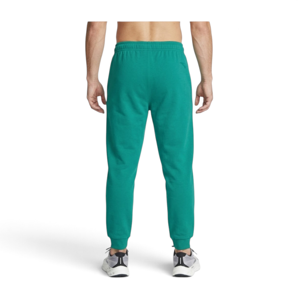 Back view of FRG ANTA emerald green basketball knit track pants on a person wearing athletic sneakers.